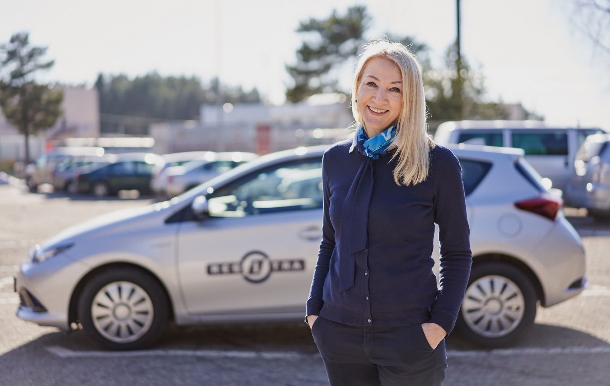 Šioje nuotraukoje matomas žmogus, stovintis priešais sidabrinį Regitros automobilį stovėjimo aikštelėje.